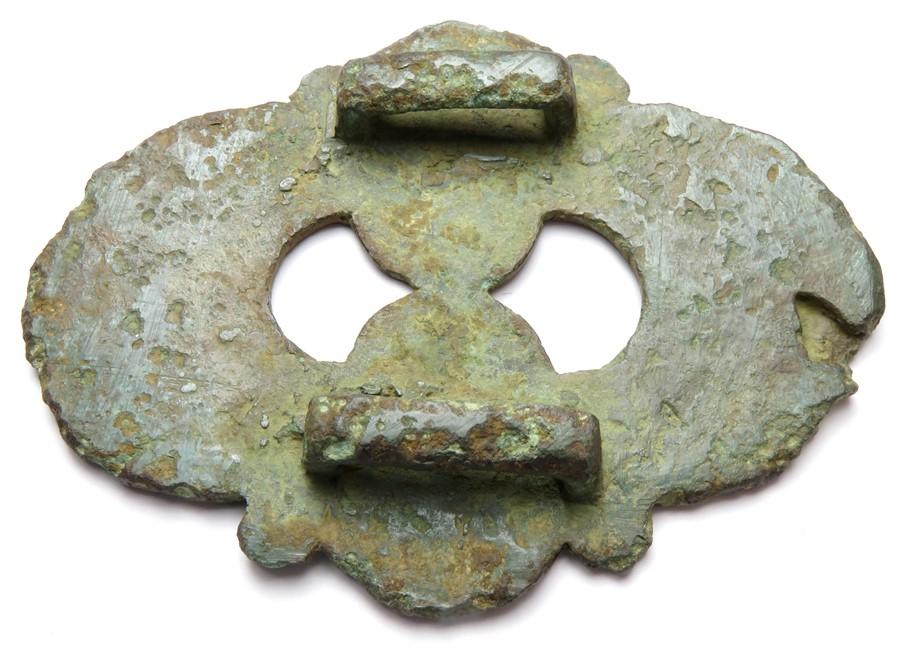 Celtic enamelled harness mount. A late Iron Age bronze 'Eared' mount from a  horse harness. The front face of the mount has champleve enamel decoration,  the main elements of which are two