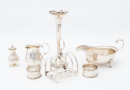 A collection of silver tableware including: a George VI oval sauceboat, on three hoof and shell feet, C-scroll handle, A Bros Ltd, Birmingham, 1947; Victorian five-bar toast rack, James Dixon & Sons, Sheffield, 1899; a George V plain Christening cup, by S Blanckensee & Son Ltd, Chester, 1939; a Georgian style pepper pot, by Josiah Williams & Co, London, 1919; a pair of napkin rings by Mappin & Webb, London, 1927 and a trumpet shaped vase, Walker & Hall, Chester 1939 - weighed, silver weighed at 