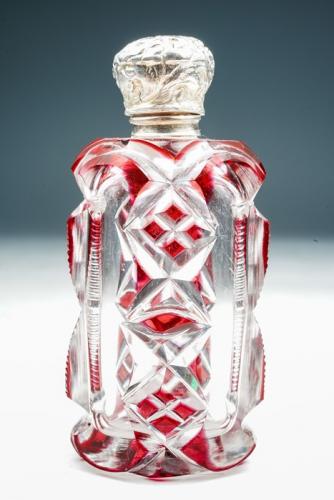 A late 19th Century red flash cut oblong perfume bottle, the silver cover chased with foliage - apparently unmarked, with glass stopper