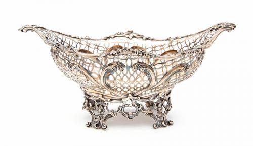 A late Victorian silver shaped oval pierced basket, the border cast with flowers and scrolls above reticulated body with heart shaped foliate motif, on openwork scroll and foliate base, Francis Boone Thomas, London, 1887, with retailer's stamp, 22.04 ozt (685.4 grams)