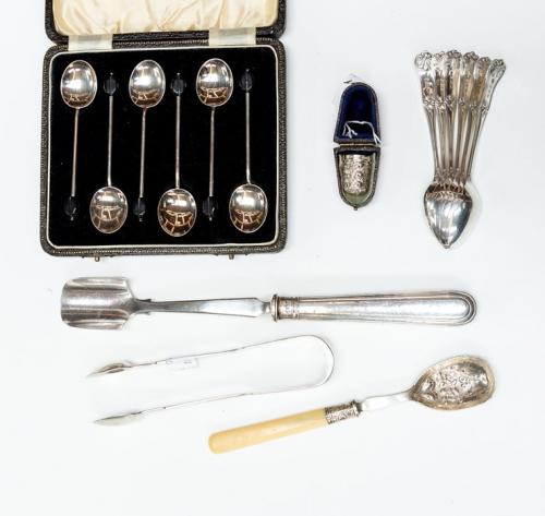 A collection of silver including: an Edwardian stilton scoop, Sheffield, 1902; a jam spoon with chased bowl, bone handle, Sheffield, 1902; Victorian fiddle pattern sugar tongs, London, 1842; a George V cased thimble, Chester, 1923 (import mark); a set of six George V teaspoons, Birmingham, 1921; and a cased set of six Coffee spoons with bean terminal, Birmingham, 1938 (6)