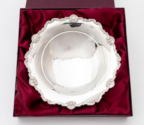 A George V silver shaped circular plain bowl, the border with rocaille and scroll decoration, on raised foot, by Adie Brothers Ltds, Birmingham, 1934 with Coronation mark, 23.5cm diam, 9.10 ozt (282.9 grams)