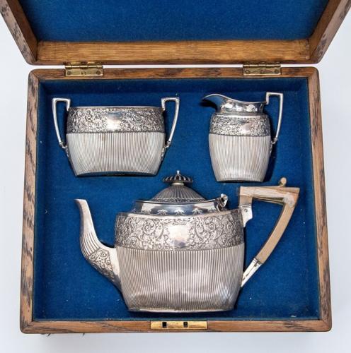 A Victorian silver tea set, comprising teapot, sugar bowl and cream jug, foliate floral and scroll decoration to upper band with fine embossed ribbed body, ebony finial, wooden handle (damaged) Sheffield, maker James Dixon & Sons, 1894, total gross weight approx 20.06 ozt, in fitted oak case