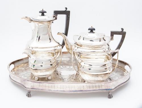 An early 20th Century silver matched four-piece tea and coffee service, Georgian style with gadroon borders on four ball feet, the tea and coffee pots with fruitwood handle and pagoda shaped finials, by Hammond, Creake & Co, Sheffield, 1910, the coffee pot 1907, gross 64.38 ozt (2,001.8 grams) together with silver-plate shaped oval engraved galleried tray (5)