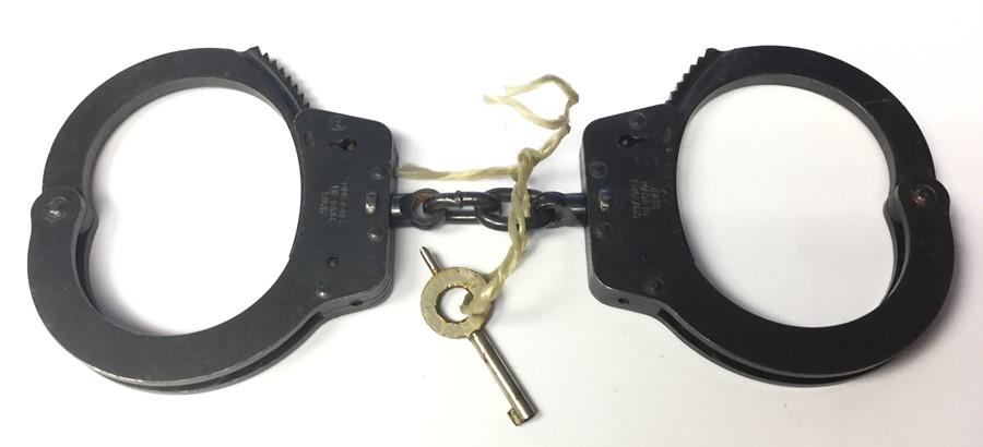 One pair of Hiatts Handcuffs with gun metal finish. Marked Hiatts Made in England Complete with key