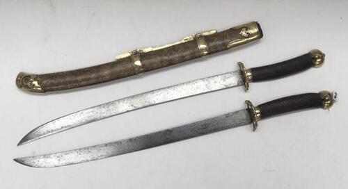 A 19th century Chinese Shuang jian paired swords or ‘butterfly knives’.
 Two short swords fitting back to back within one scabbard.
 Both have wrythen carved wooden grips, brass half pommels and guards, the latter with bamboo moulded outline.
 Steel singl