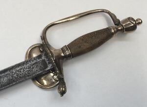 A 1796 pattern infantry officer's sword.
 Brass fold down guard, knuckle guard and pommel.
 Wooden handle that would of formally had a wire binding around it.
 Steel single edged blade, with fuller to both sides and flat spine.
 No visible makers marks or - 2