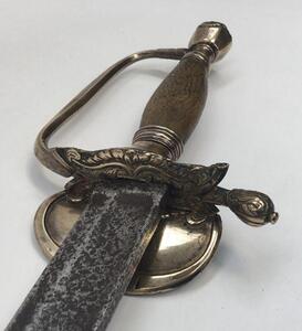 A 1796 pattern infantry officer's sword.
 Brass fold down guard, knuckle guard and pommel.
 Wooden handle that would of formally had a wire binding around it.
 Steel single edged blade, with fuller to both sides and flat spine.
 No visible makers marks or - 3