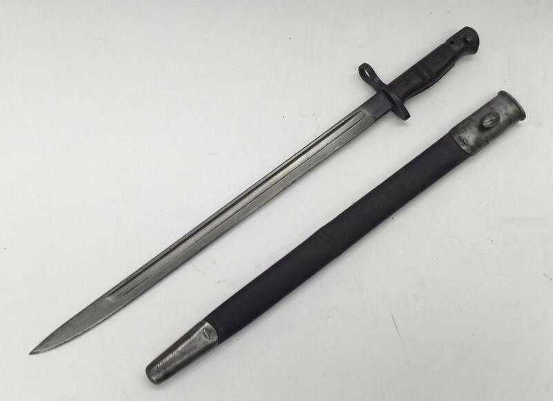 An American P1914 bayonet, with makers mark for Remington and 1917 date at the ricasso.
 Wooden slab grips with usual double grooves to each side.
 Blued pommel, cross guard and ricasso area.
 Single edged blade with fuller to both sides.
 Black leather s