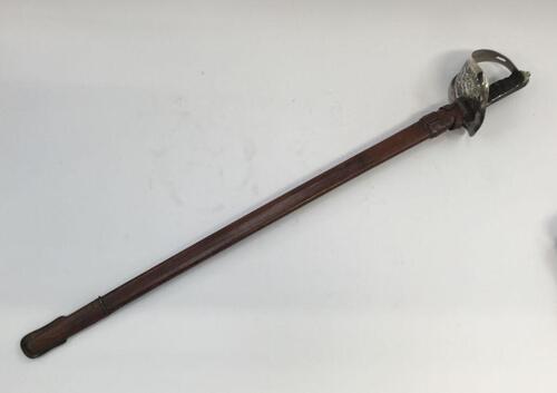 A WW1 era 1897 pattern infantry officers sword with leather field scabbard.
 Standard pieced nickel plated guard, with cypher of George V.
 Shagreen grip with wire binding, chequered steel backpiece and knopped pommel.
 Steel single edged blade with singl