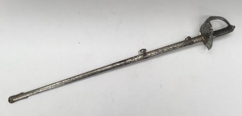 A WW1 era 1897 pattern infantry officer's sword, of piquet weight.
 Nickel plated pierced guard, with George V cypher and crown.
 Slot to guard near pommel for attaching sword knot.
 Fish skin grip with twisted copper wire binding, plus chequered backpiece.
 Straight blade with single fuller, seemingly unsharpened.
 Etched decoration of George V cypher, royal coat of arms, and foliage patterns.
 Proof mark and makers mark for Hawkes & Co to the ricasso.
 8683 stamped to the flat spine of the bla