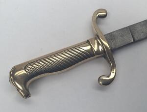 A 19th century Prussian M1864 NCO’s short sword or side arm.
 Brass handle with diagonally grooved grip to one side, and a beak shaped pommel.
 Curled quillons to the cross guard.
 Straight steel single edged blade, un-fullered with a flat spine.
 No appa - 2