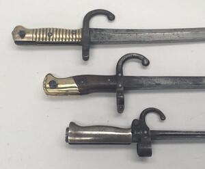 3 19th century French sword bayonets.
 To include, a M1886 Lebel, with hooked quillon and cruciform blade (no scabbard).
 A Gras bayonet, with wooden grips and brass pommel, dated 1876 to the flat spine (no scabbard).
 And a Chassepot bayonet, with ribbed - 3