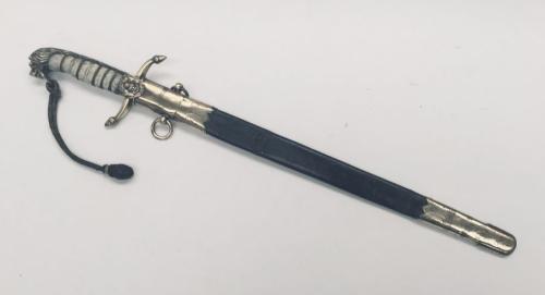 A 19th century Victorian British Navy midshipman’s dirk.
 Brass cross guard with integral release catch, fouled anchor langet, and acorn tipped quillons.
 Lion’s head pommel, with its mane forming the backpiece.
 Wire binding to the grip, which would of originally had a fish skin covering, but this would appear to have perished.
 Brass ring through the lions mouth, onto which is fitted a bullion dress knot.
 Steel single edged blade, with etched decoration, including Queen Victoria’s VR cypher a