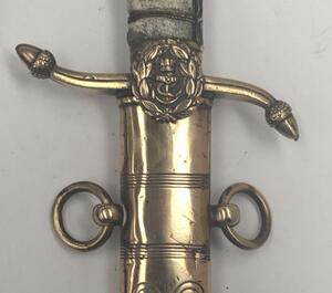 A 19th century Victorian British Navy midshipman’s dirk.
 Brass cross guard with integral release catch, fouled anchor langet, and acorn tipped quillons.
 Lion’s head pommel, with its mane forming the backpiece.
 Wire binding to the grip, which would of o - 5