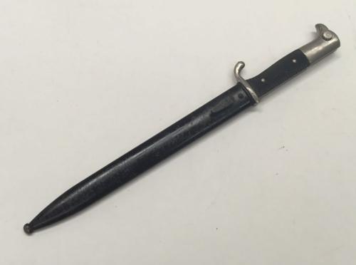 A WW2 era German dress bayonet with associated scabbard.
 Nickel plated pommel and cross guard, with red felt insert to the morticed slot.
 Black chequered Bakelite grips with two retaining rivets.
 Blade marked AC with scales logo for Alex Copel, with single edge and fuller to both sides.
 Black painted metal scabbard with frog stud.
 Approximately 40.2cm in length when in the scabbard.
 Condition: generally very good.
 Almost all the nickel plating remains to the cross guard and pommel, with w