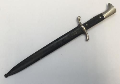 A WW2 era German fireman’s dress dagger, with associated scabbard, Carl Eickhorn of Solingen.
 Nickel plated pommel, chequered black Bakelite grips secured by 2 rivets.
 S shaped nickel plated cross guard.
 Nickel plated single edged blade with fuller to both sides, leather washer at ricasso.
 Black painted scabbard with frog stud.
 Approximately 40cm length when in scabbard.
 Condition: generally good.
 Small amount of plate loss and mottling to pommel and cross guard.
 Scabbard showing some pa