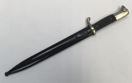 WW2 era German dress bayonet with associated scabbard.
 Nickel plated pommel, cross guard and blade, the latter single edged and with fuller to both sides.
 Original leather washer at ricasso.
 Black painted scabbard with frog stud.
 The item appears to be lacking any makers mark.
 Approximately 40.5cm length when in scabbard.
 Condition: very good.
 Some dulling to the nickel finish on the pommel and cross guard.
 The blade is clean and bright with only minor wear.
 The scabbard is very good, w