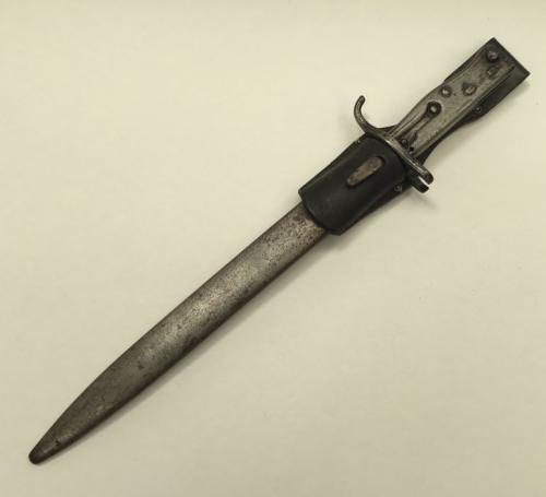 Scarce WW1 German Mauser ersatz bayonet.
 All steel construction, with push button release catch on the pommel.
 Single edged steel blade with fuller to both sides.
 The cross guard has the distinctive open muzzle ring, which allowed to be used on captured French Lebel or Russian Mosin-Nagant rifles.
 Complete with steel scabbard and leather frog, the latter dated 1931.
 The bayonet appears to be undated, but there is a faint inspection stamp to the spine of the blade.
 Approximately 47cm length