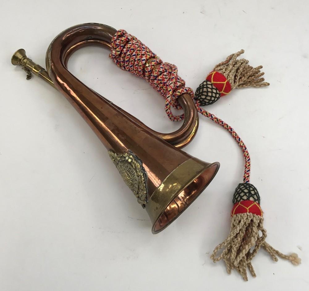 A vintage military style brass and copper bugle. Fitted with a brass Argyll  & Sutherland Highlanders badge, a detachable mouthpiece, and a cord grip.  Notes: no apparent maker marks or dates. Unknown