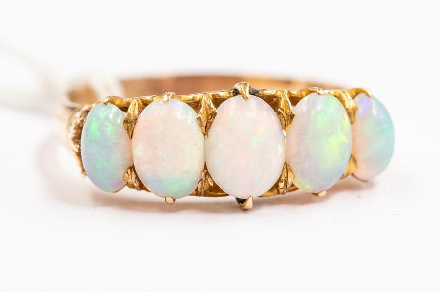 An opal and 14ct gold ring, set with five graduated oval opals, claw ...
