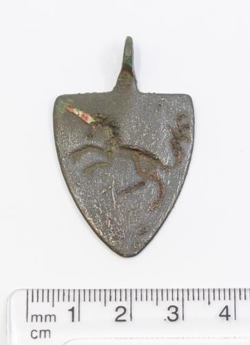 Medieval copper alloy Pendant depicting what appears to be a unicorn as there is still a red/white striped enamel horn protruding from the creatures head, very similar to the unicorn of Harling. H33mm (loop not included). W27.4mm. 9.84g.