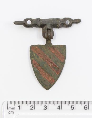 Medieval large copper alloy shield Pendant and hanger showing three red enamel chevrons diagonally top left to bottom right. H34.4mm (not including hanger) W27.6mm. 18.18g.